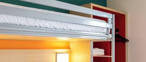 A bunk bed with a wooden headboard, a red wardrobe, and a small bedside lamp.