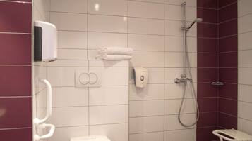 Une salle de bain moderne équipée de toilettes, d’une douche et d’un sèche-mains.