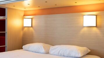 A modern hotel room with a large bed, two bedside tables, a wardrobe, and two wall-mounted lights.