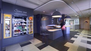A modern hotel lobby with a reception desk, vending machines, and a check-in counter. - Hôtel Première Classe Thionville (Thionville)
