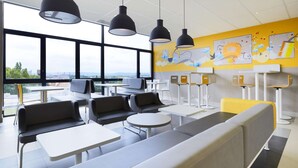 A modern waiting area with seating, tables, and artwork on the walls. - Hôtel Première Classe Thionville (Thionville)
