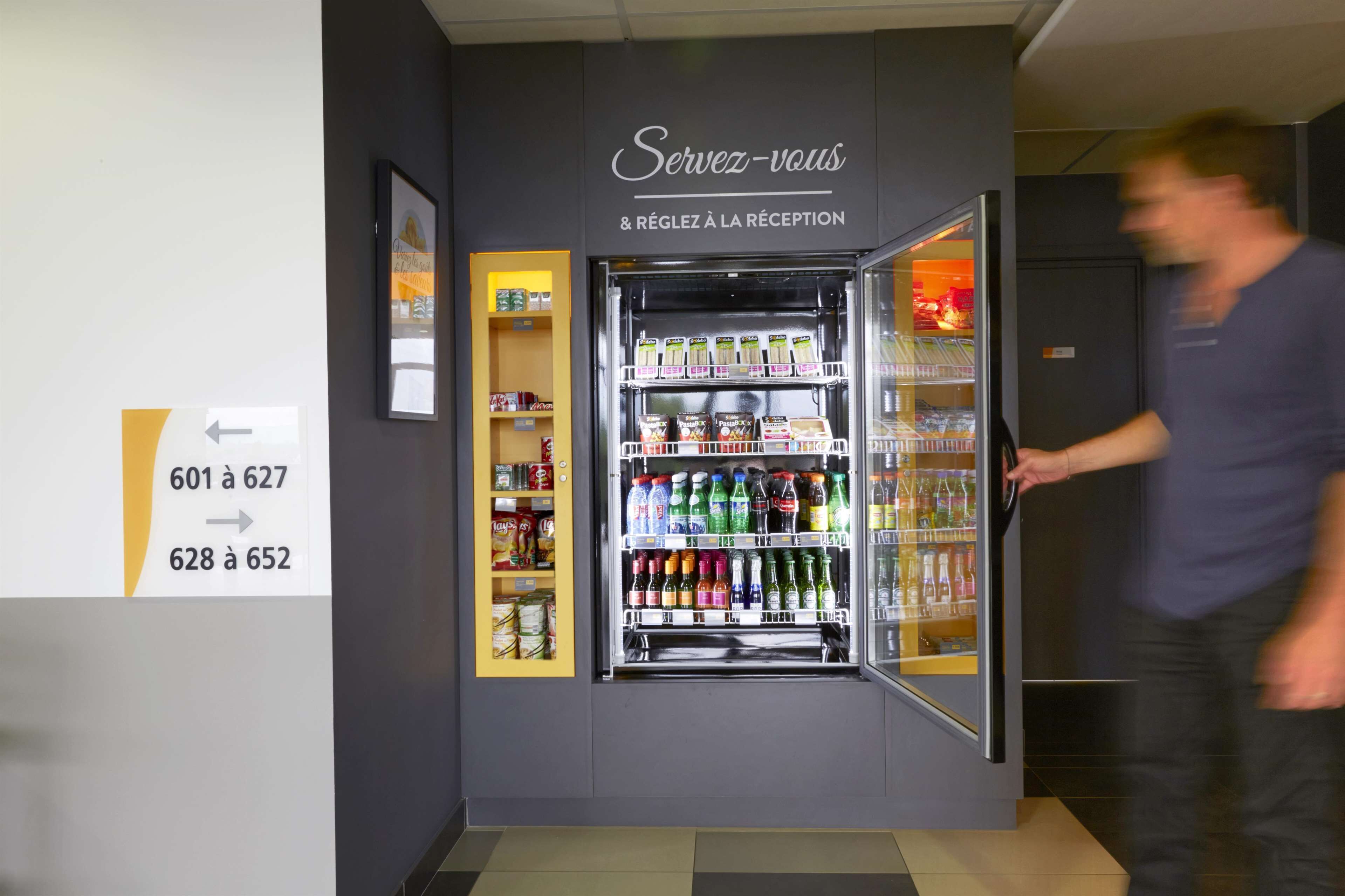 Zona de recepción de un hotel, con un refrigerador lleno de bebidas y aperitivos.
