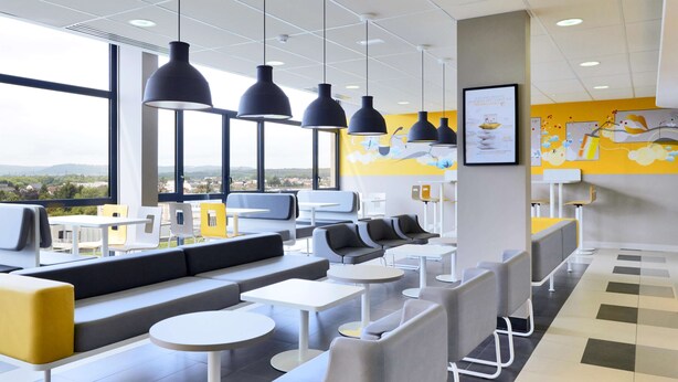 A modern cafe with seating areas, tables, and pendant lighting. - Hôtel Première Classe Thionville (Thionville)