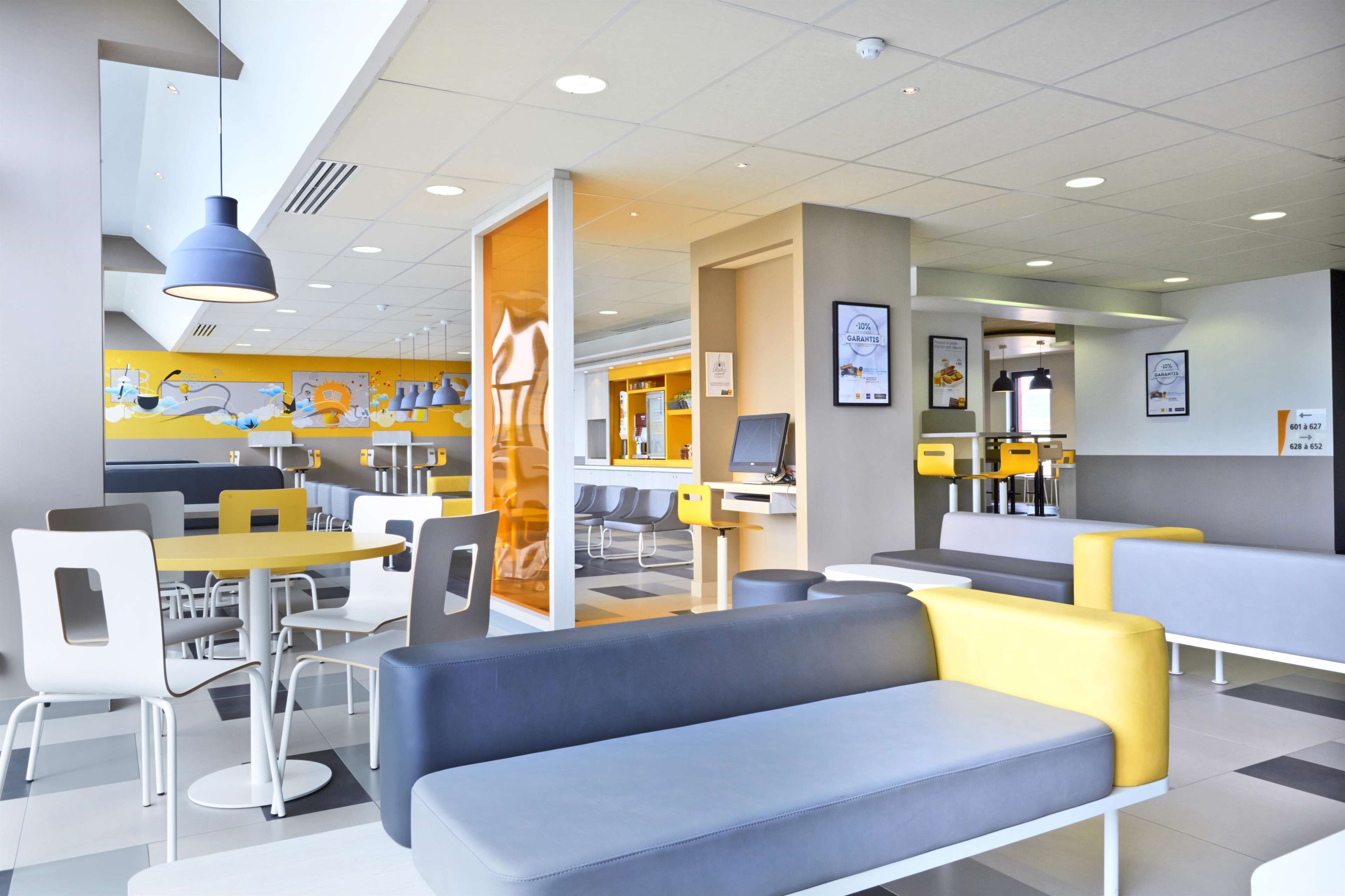 A modern cafe with seating areas, tables, and a counter.