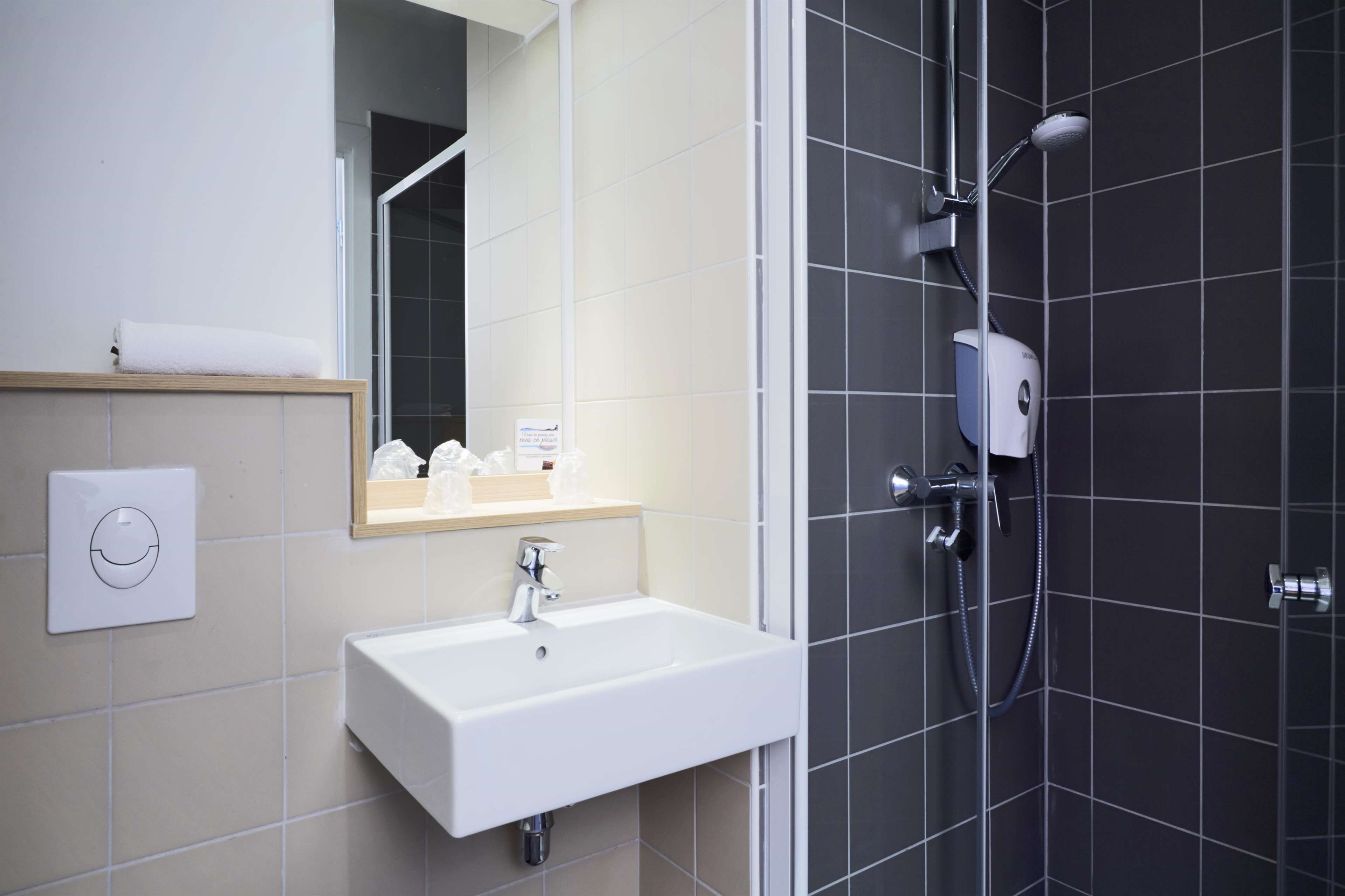 Ein modernes Badezimmer mit einem weißen Waschbecken, einem Spiegel und einer Duschkabine.