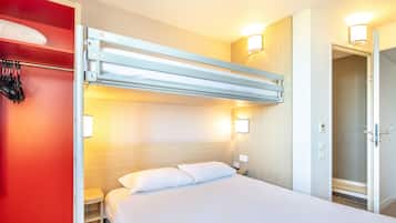 A hotel room with a bunk bed, a bedside table, a nightstand, and a bathroom door.