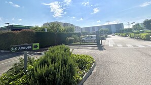 A parking lot with a sign for B&B ACCUEIL, a building in the background, and a clear sky. - B&B HOTEL Lyon Aéroport St Quentin Fallavier (Saint-Quentin-Fallavier)