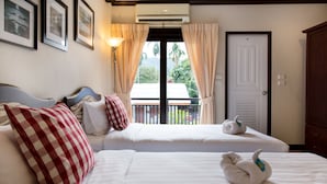 A hotel room with two beds, a balcony, and a door. - Garden Home Resort (Koh Samui)