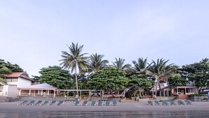 A beachfront hotel with rows of sun loungers and palm trees. - Sans Souci Samui (Koh Samui)