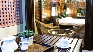 A cozy outdoor seating area with wicker furniture, a small table, and a potted plant. - Sans Souci Samui (Koh Samui)