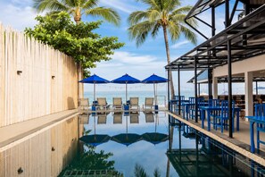A poolside area with lounge chairs, umbrellas, and a view of the ocean.