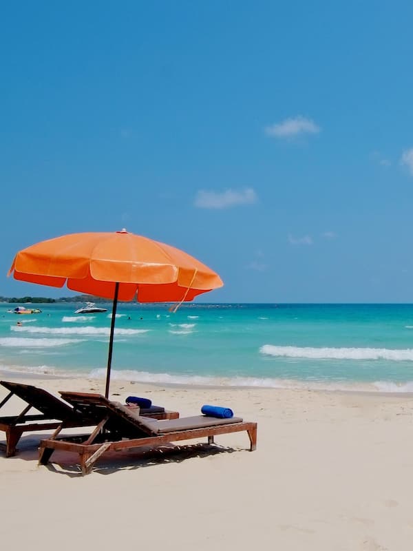 Praia particular, areia branca, espreguiçadeiras, guarda-sóis