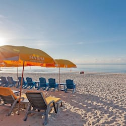 Praia particular, areia branca, espreguiçadeiras, guarda-sóis