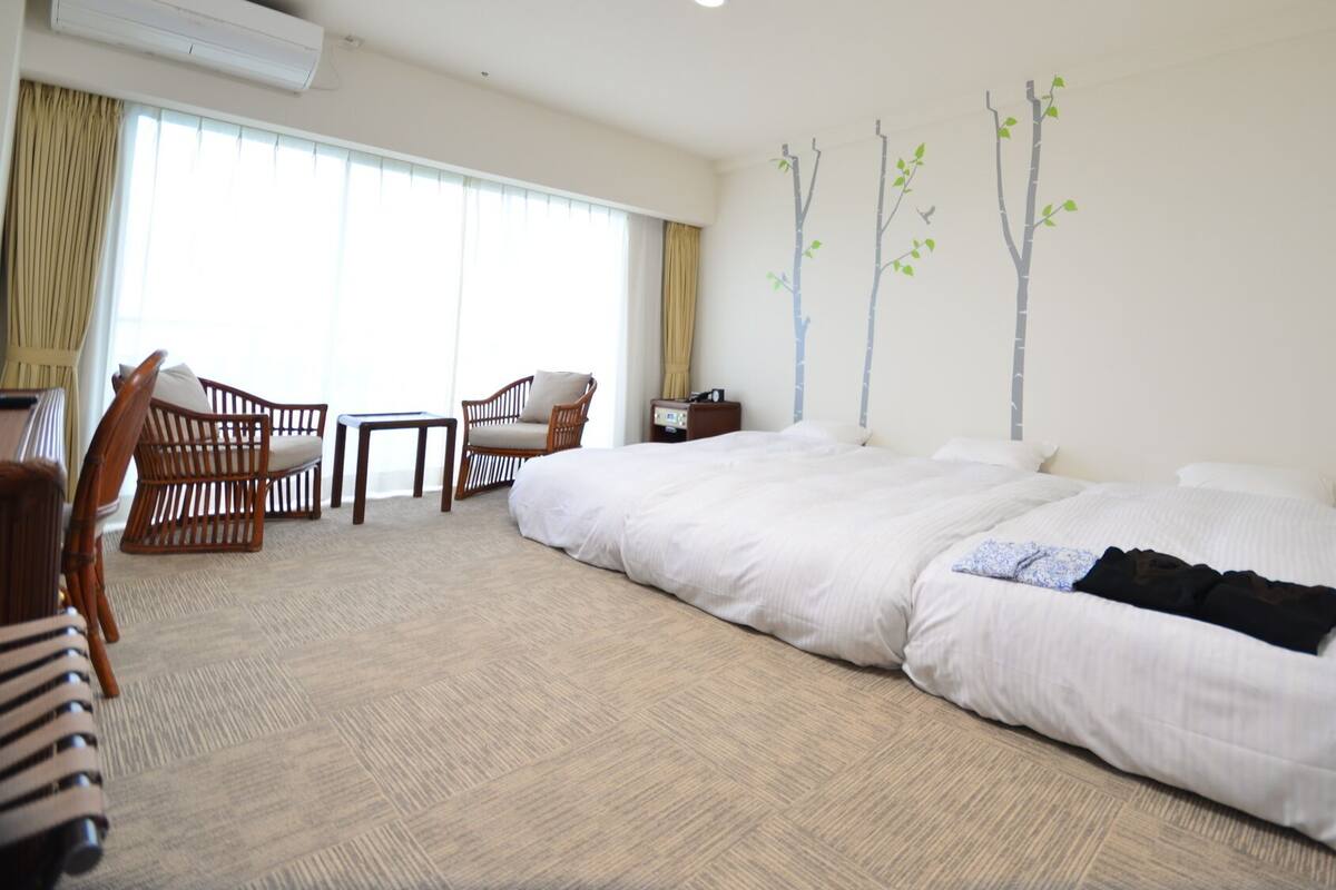 A hotel room with a large bed, two wooden chairs, a small table, and a nightstand.