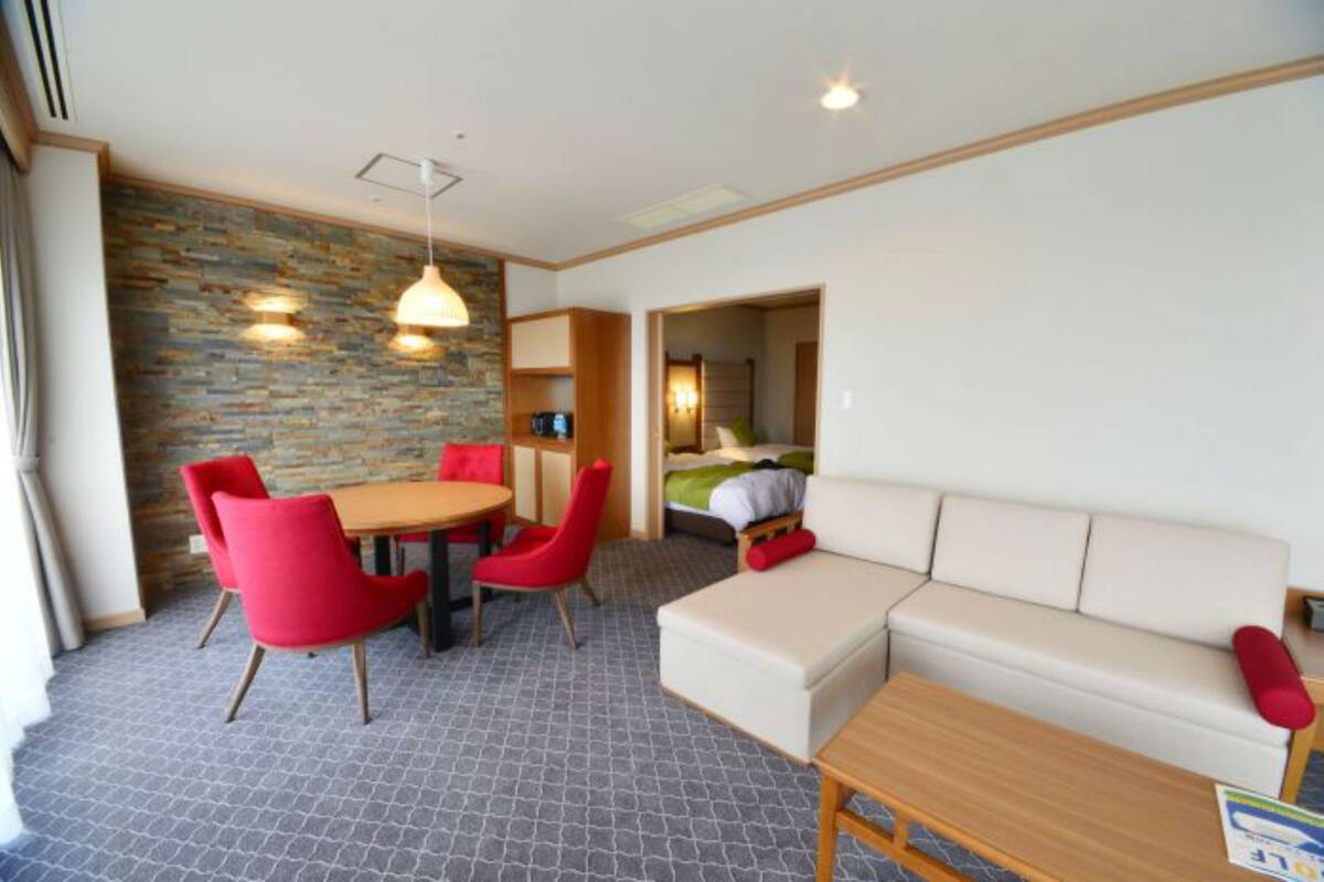 A compact hotel room with a dining area, a sofa, and a bed.