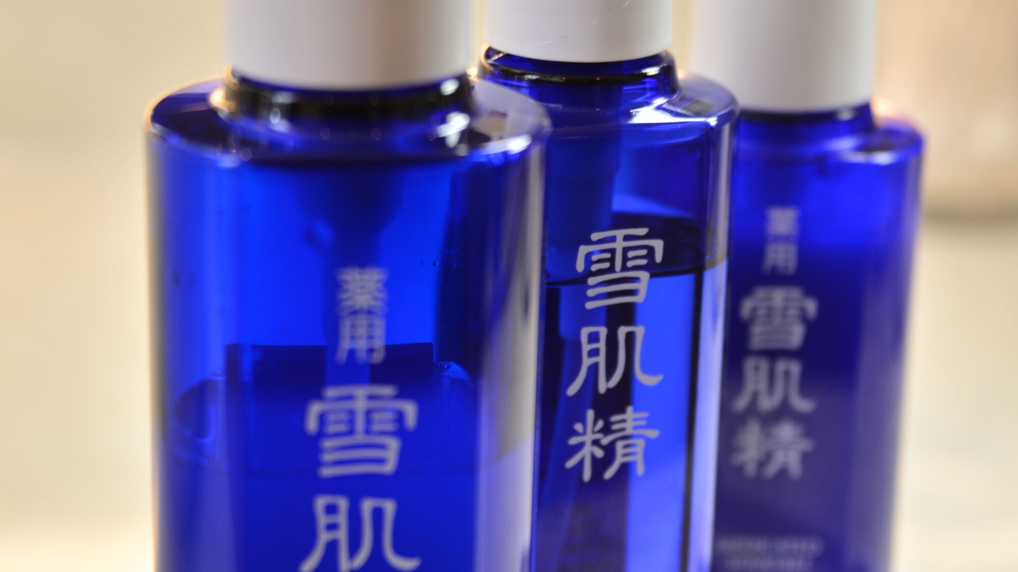 Trois bouteilles bleues avec des bouchons blancs et du texte en chinois.