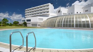 A swimming pool with metal railings, surrounded by a modern building with a curved glass structure. - Satsuma Resort Hotel (Satsuma)