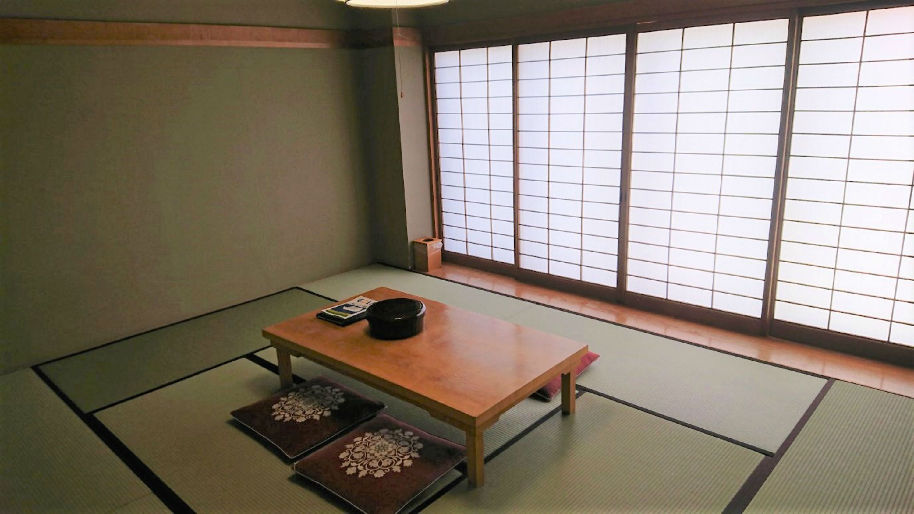 A traditional Japanese room with tatami flooring, a low wooden table, and shoji sliding doors.