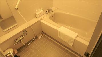 Un bagno con vasca, WC e lavandino. Prodotti da bagno a parete e un asciugamano appeso alla vasca.
