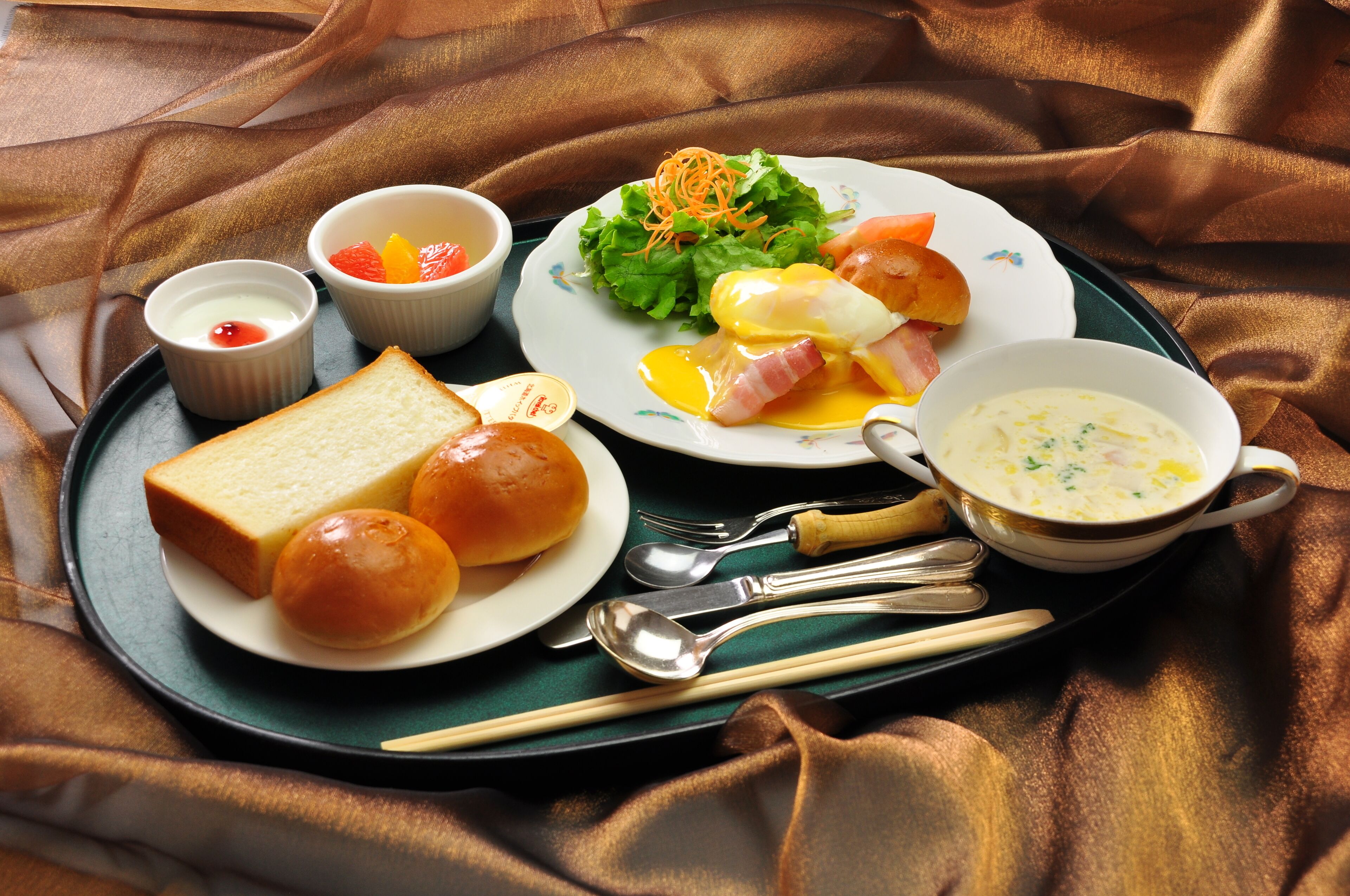 A tray with breakfast items including eggs, toast, soup, and salad.