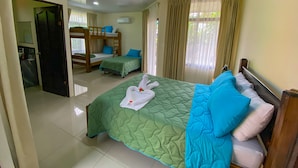 Quarto de hotel com beliche, uma cama de solteiro e banheiro.