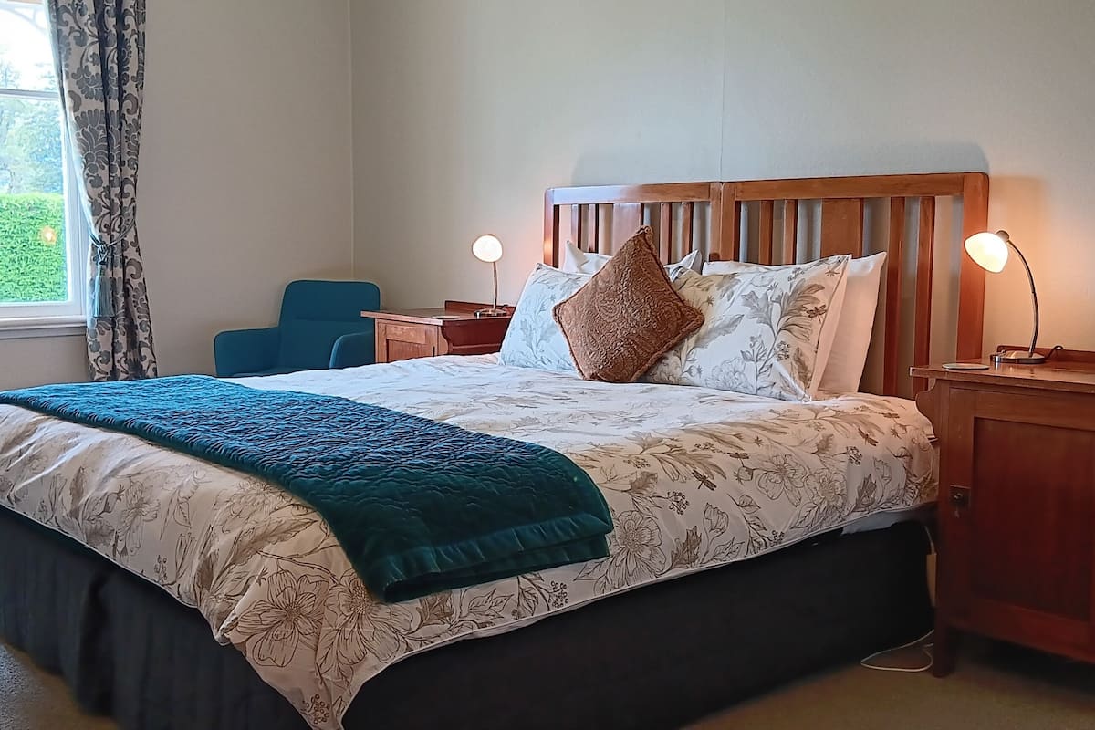 A neatly arranged bedroom with a bed, bedside tables, and a window with curtains.
