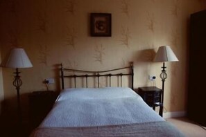 Una stanza con un letto, due comodini e due lampade a parete.