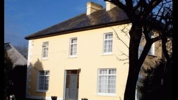 A two-story building with a symmetrical facade, a central entrance, and a pitched roof. - The Orchard (Newcastle West)
