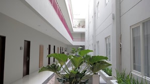 A modern hotel corridor with a central atrium, featuring a glass ceiling and potted plants. - Lombok Plaza Hotel & Convention (Mataram)