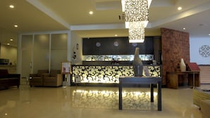 A modern hotel lobby with a reception desk, seating area, and a decorative wall. - Lombok Plaza Hotel & Convention (Mataram)