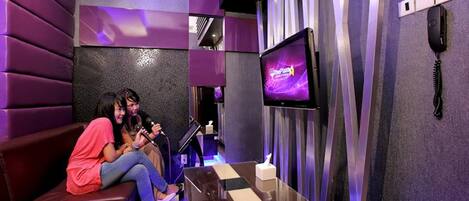 A modern room with a purple and black color scheme, a flat-screen TV, a telephone, and a small table.