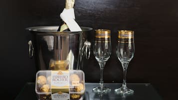 Una botella de champán en un balde de metal, dos copas de champán vacías y una caja de bombones Ferrero Rocher.