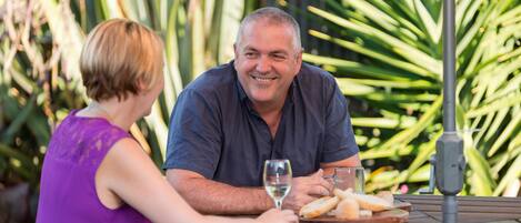 A man and a woman sitting at an outdoor table with a glass of wine and bread.