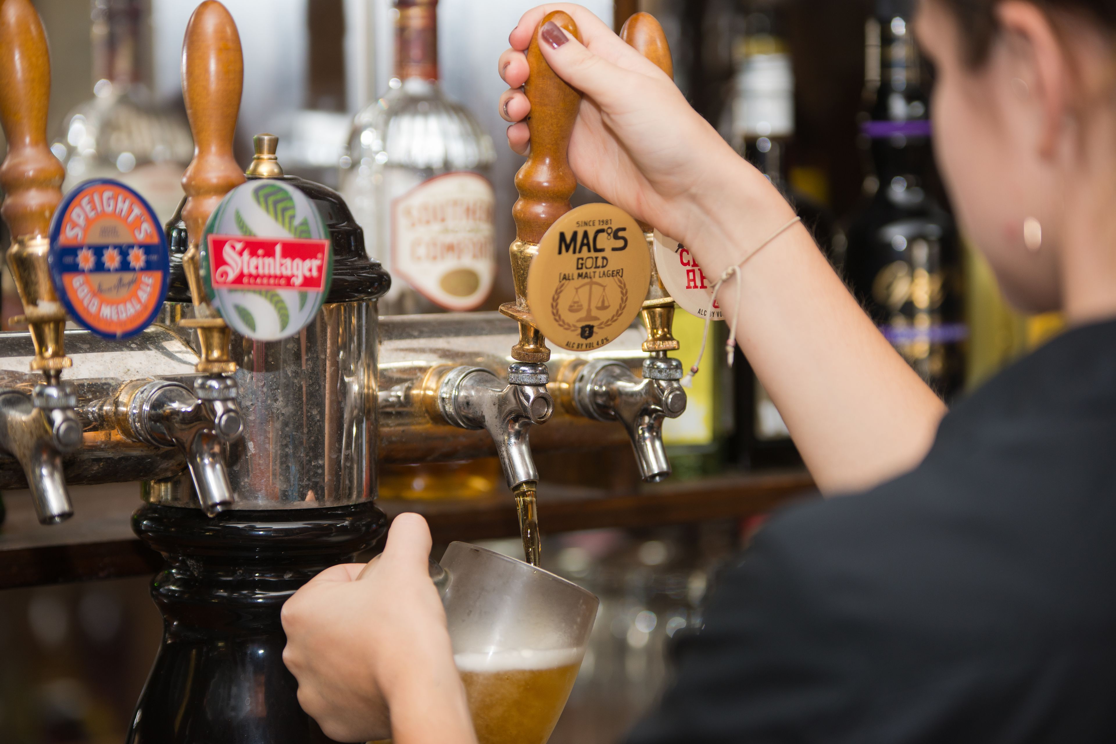 Un bar con varias griferías, incluyendo marcas como Steinlager y MAC'S Gold.