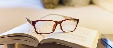 Un livre sur lequel sont posées des lunettes, placé sur une surface en bois.