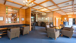 Eine großzügige Lobby mit Holzvertäfelung, eine zentrale Sitzecke mit Sofas und einem Couchtisch sowie ein Empfangsschalter im Hintergrund.