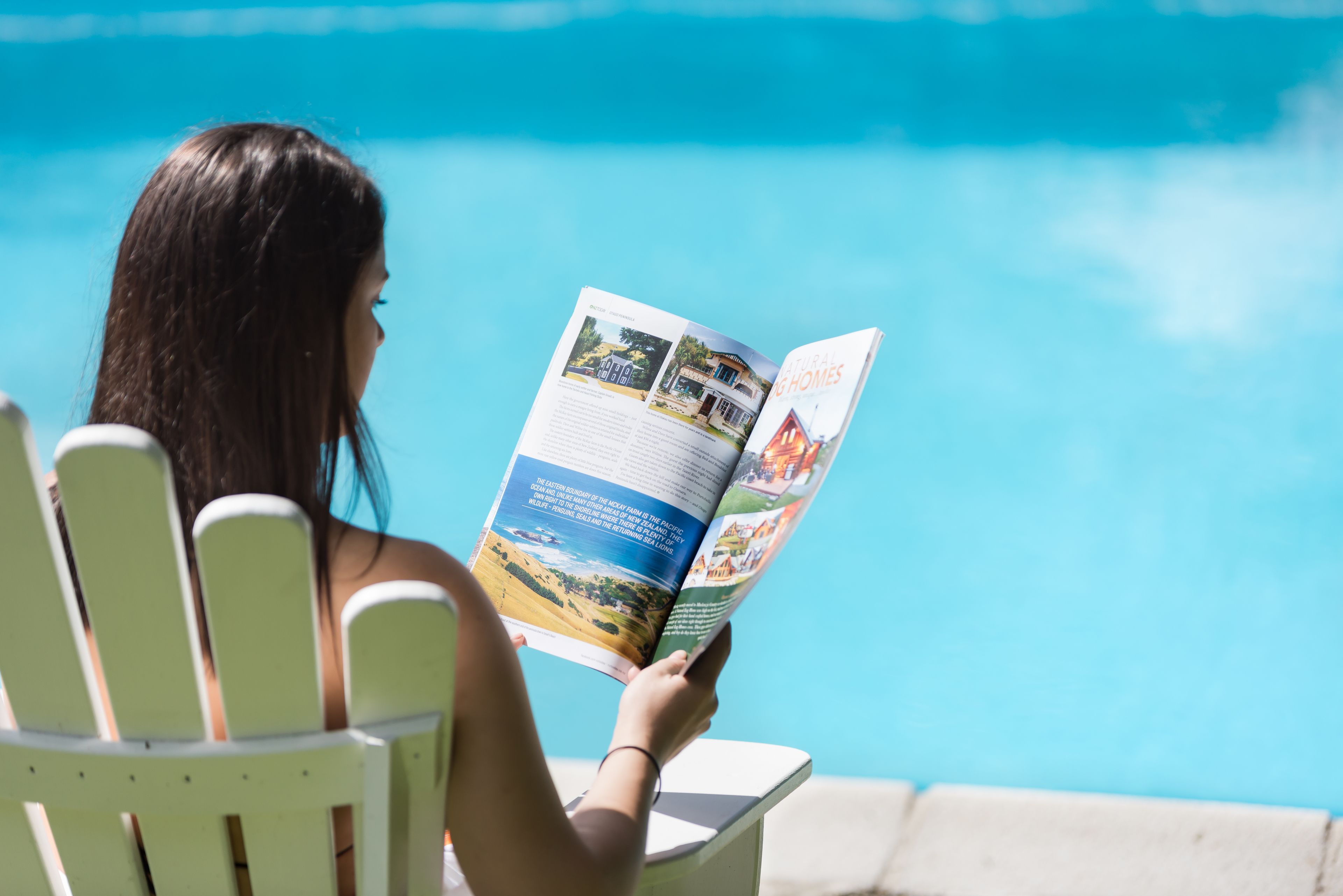 A person reading a brochure by a pool.
