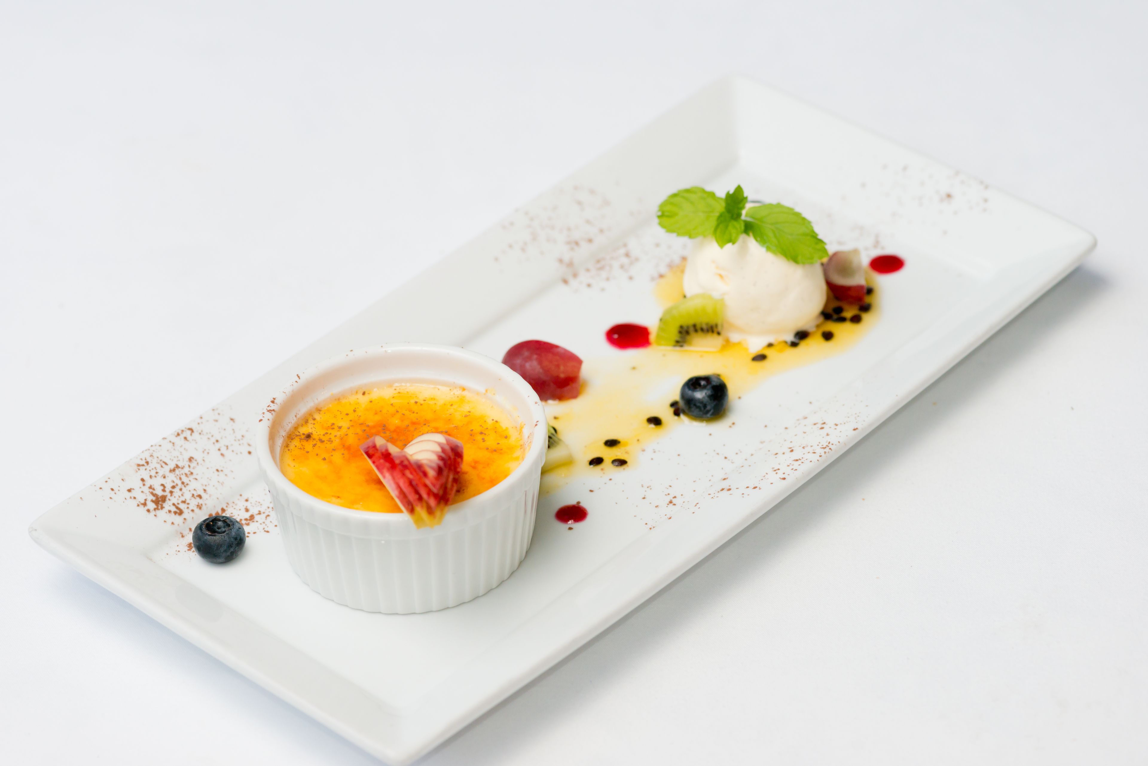 A dessert plate with a custard dish, ice cream, and berries.