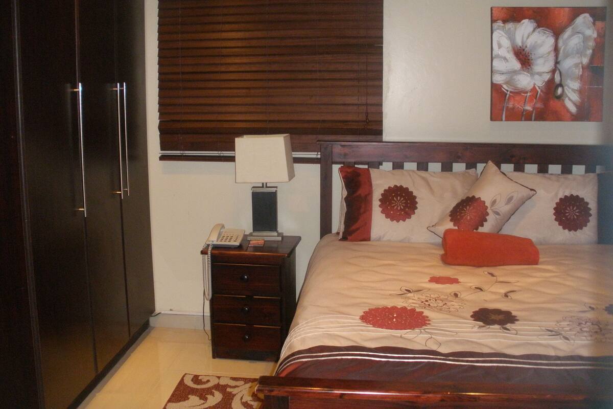 Un dormitorio con cama, mesita de noche, lámpara, teléfono y armario.
