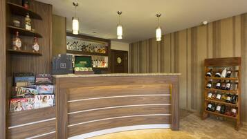 A reception area with a wooden reception desk, magazines, a liquor display, and a wine rack.