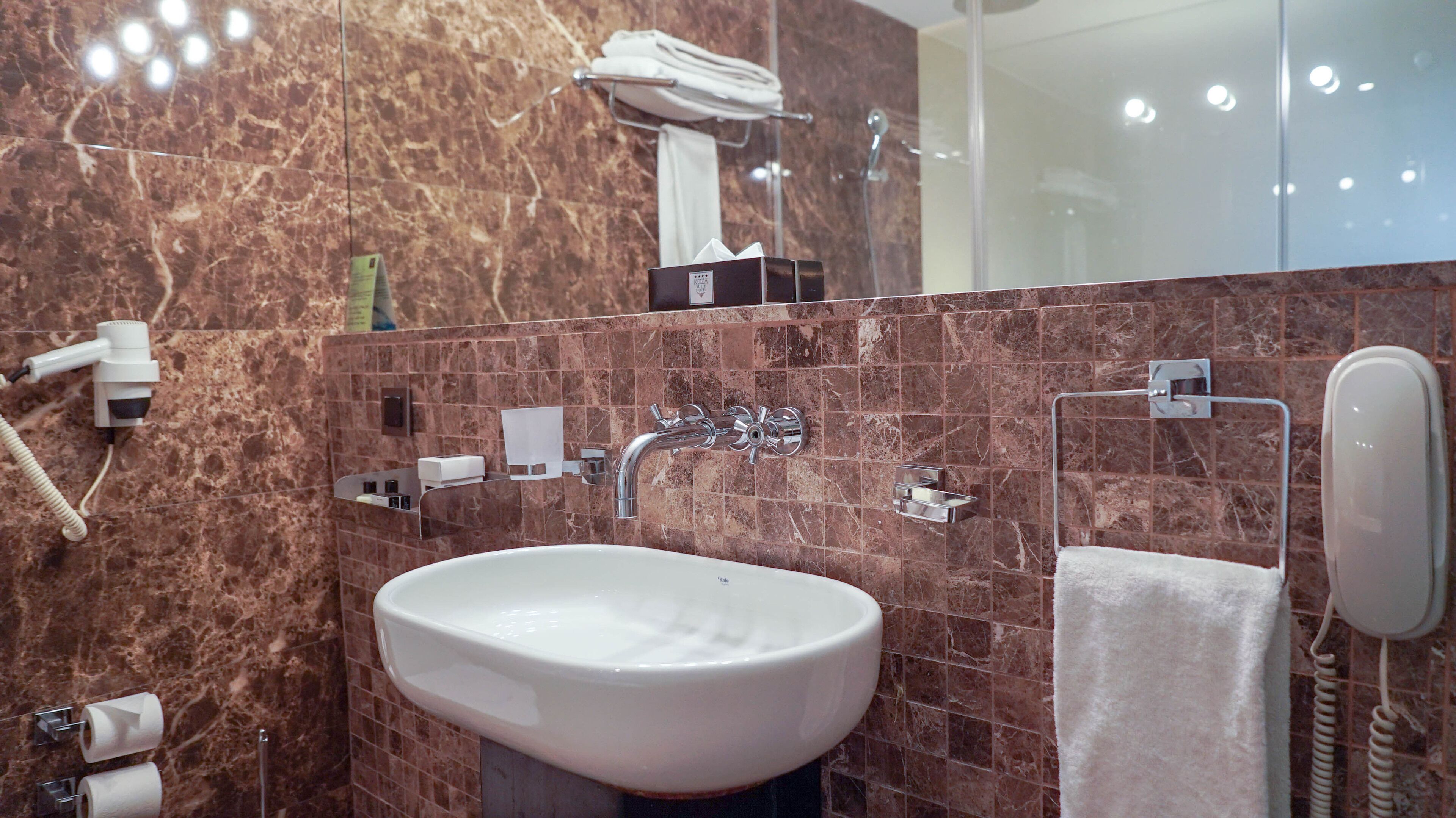 A bathroom with a white sink, a towel rack, a mirror, and a shower area.