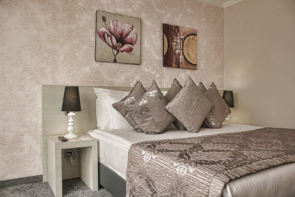 A neatly arranged bedroom with a bed, pillows, a nightstand, and a lamp.