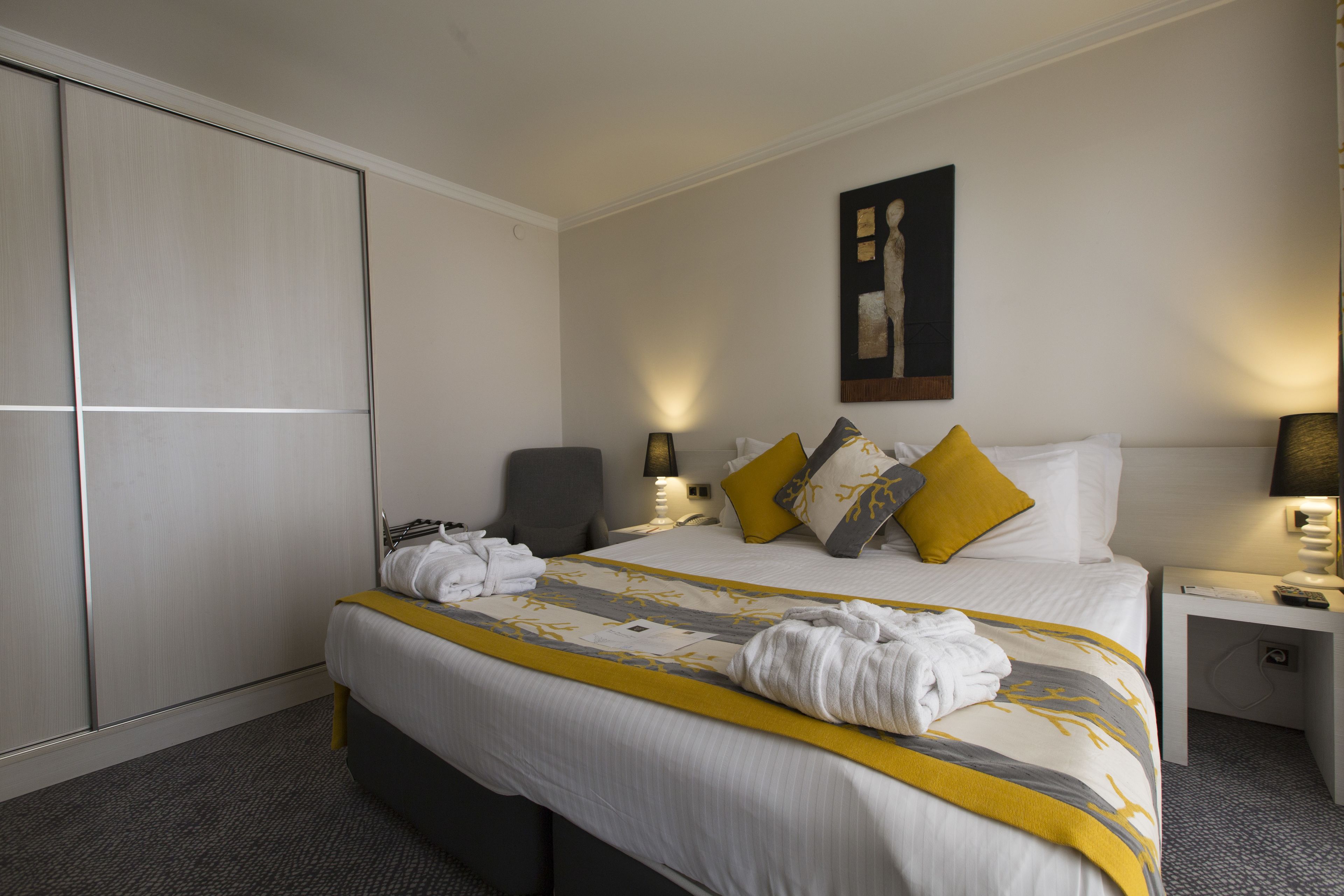 Una habitación de hotel con una cama, un escritorio, una silla y un armario.
