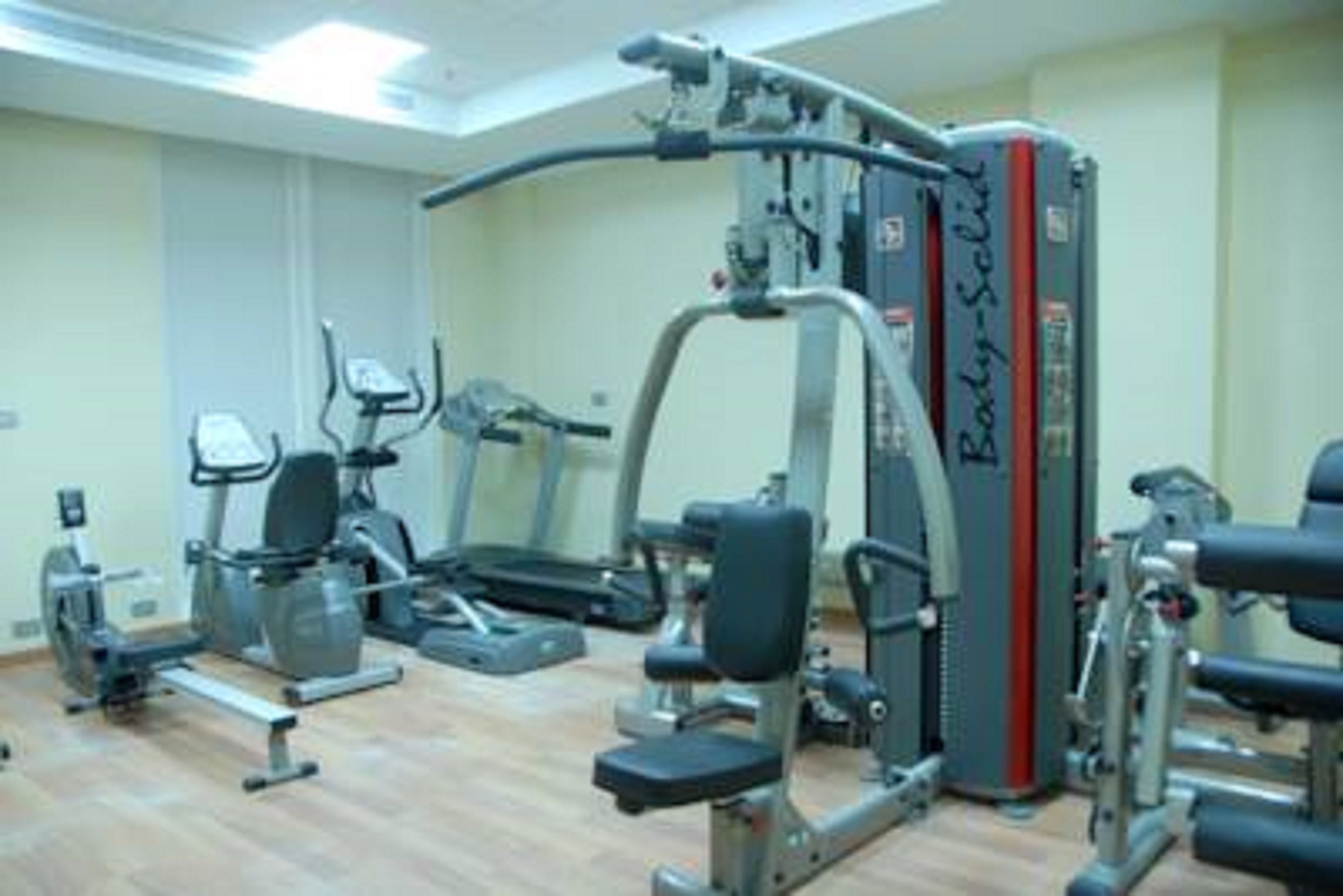 Un gimnasio con máquinas de cardio, equipo de levantamiento de pesas y una prensa de banca.