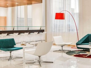 A modern lobby with a glass partition, white chairs, a red floor lamp, and a large mirror. - Ibis Yanbu Saudi Arabia (Yanbu)