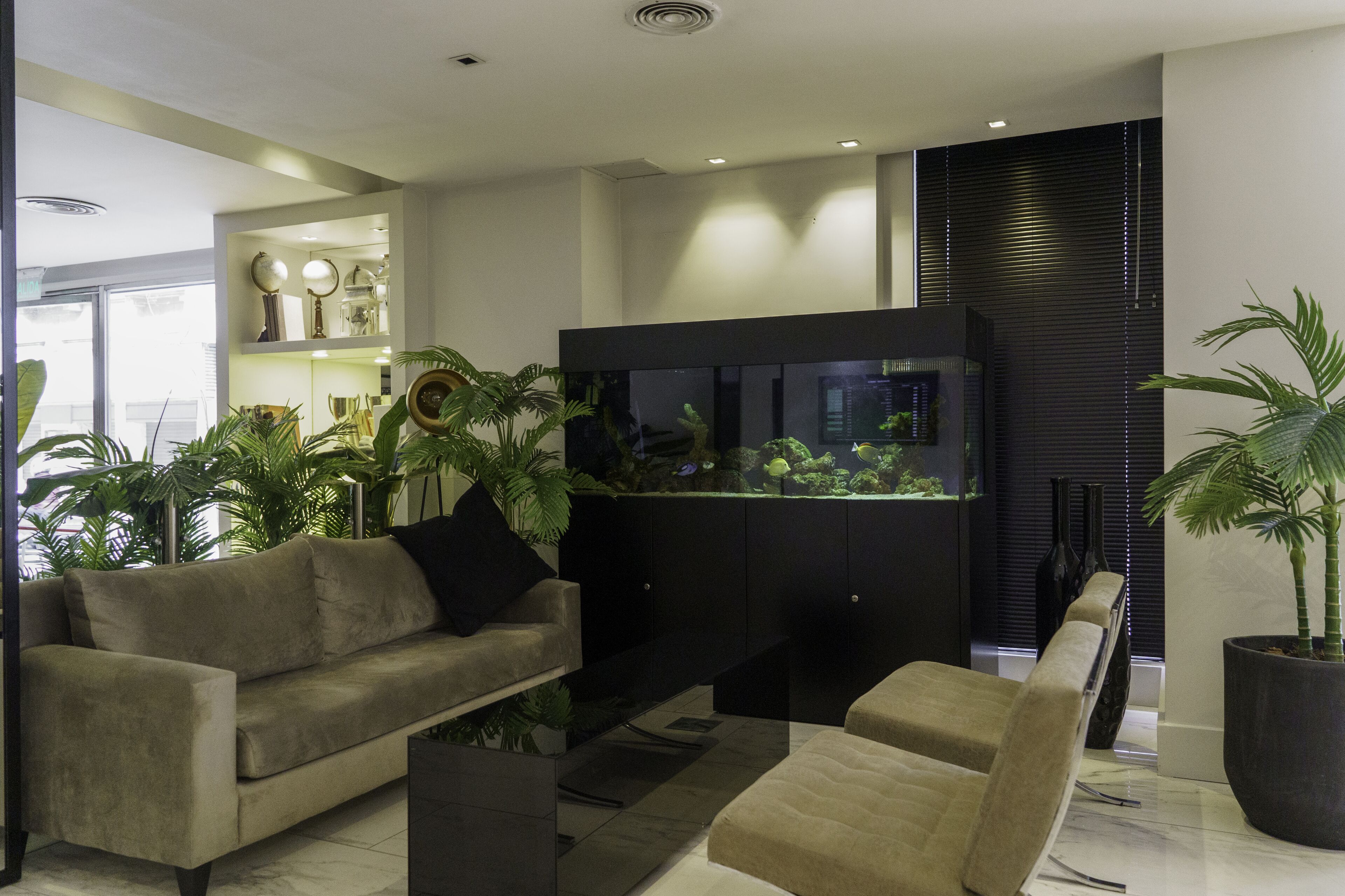 A modern living room with a sofa, a coffee table, and a large aquarium.
