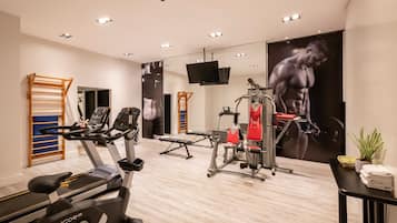 A gym with exercise equipment, a treadmill, and a mirror wall with a large poster.