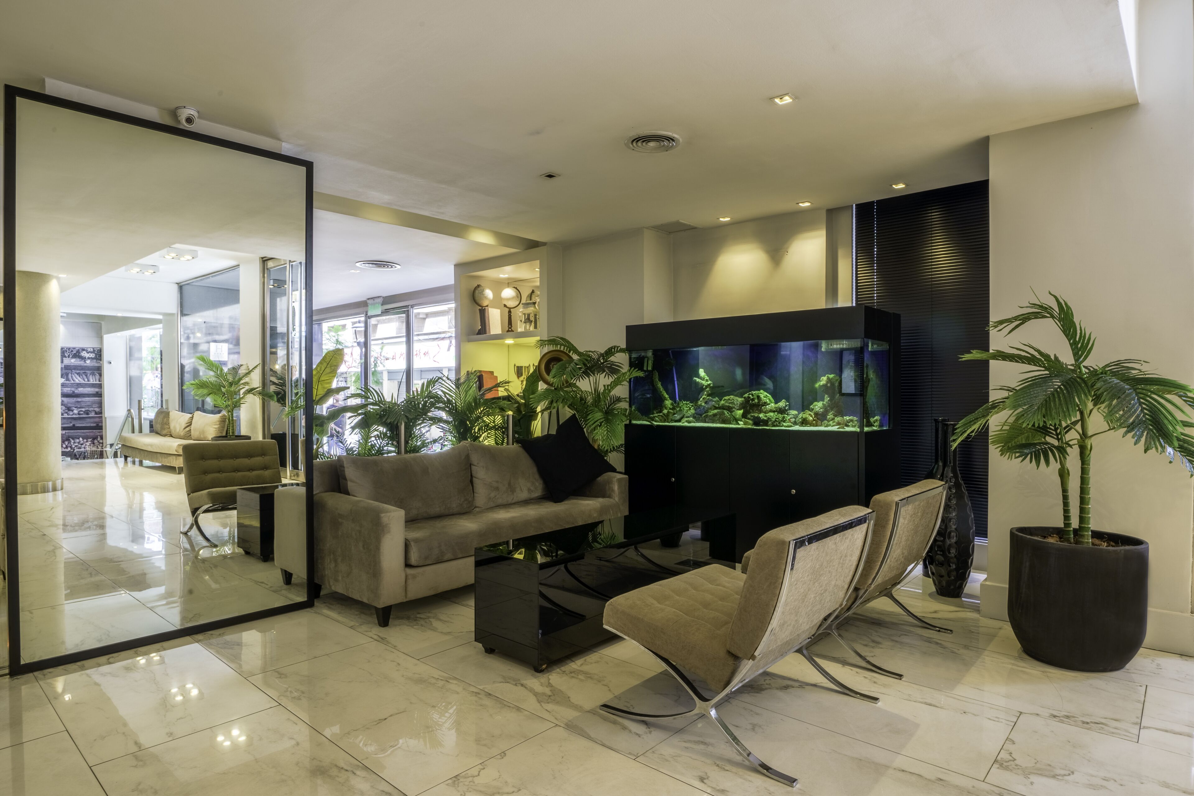 A modern living room with a sofa, armchair, coffee table, and a large aquarium.
