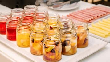 Un buffet de petit-déjeuner proposant une variété d’aliments et un grand récipient en verre rempli de jus d’orange.