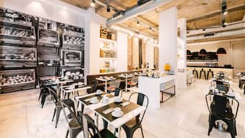 Un restaurante moderno con paredes de ladrillo visto, vigas de madera y diversas opciones de asientos, incluyendo mesas y cabinas.